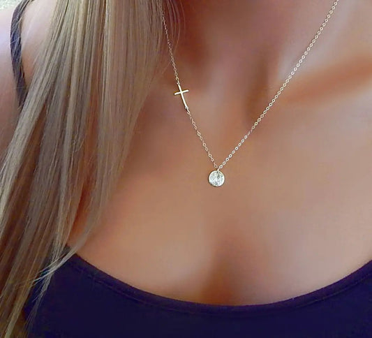 Fingerprint necklace with sideways cross hangs on the neck of a model.