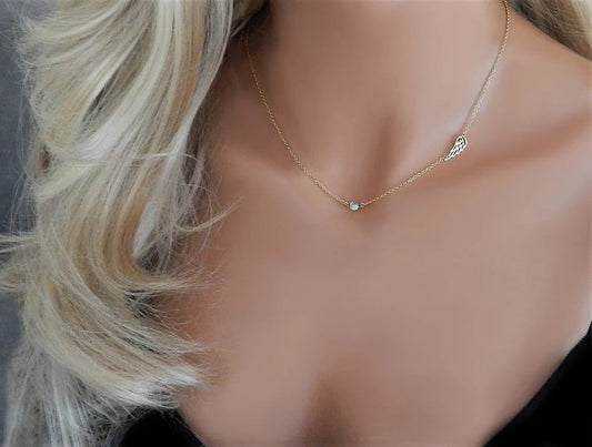 Gold filled memorial necklace with angel wing and birthstone is worn on the neck of a model with blonde loose curls.