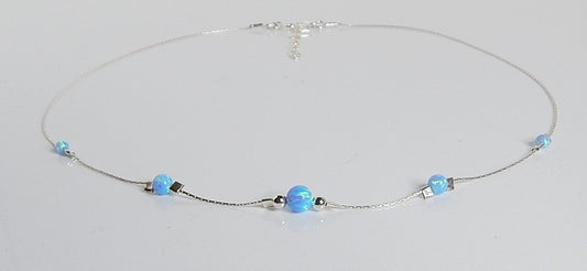 Silver choker necklace with 5 blue opal gemstones displayed on a white counter.