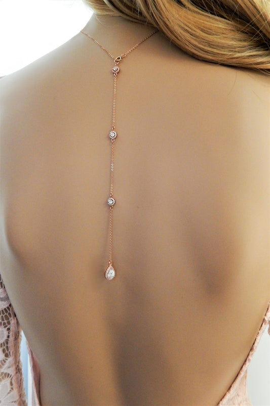 Mannequin wearing a rose gold necklace with backdrop and cz diamonds with a backless dress.