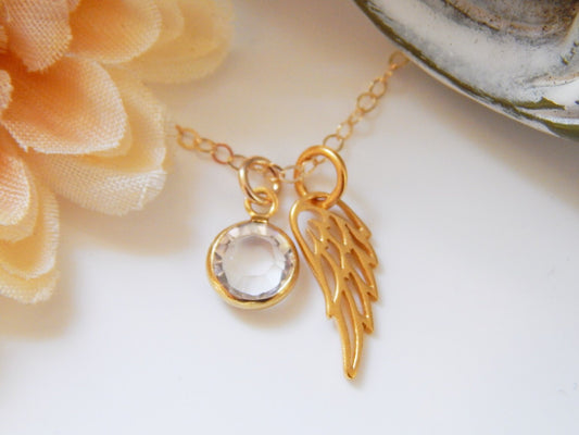 Gold wing necklace charm with a clear birthstone charm on a necklace chain.