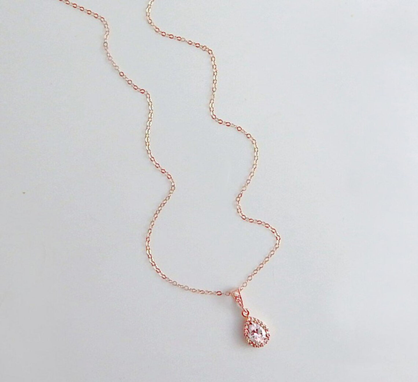 Rose gold necklace with teardrop diamond CZ pendant on a plain white background.