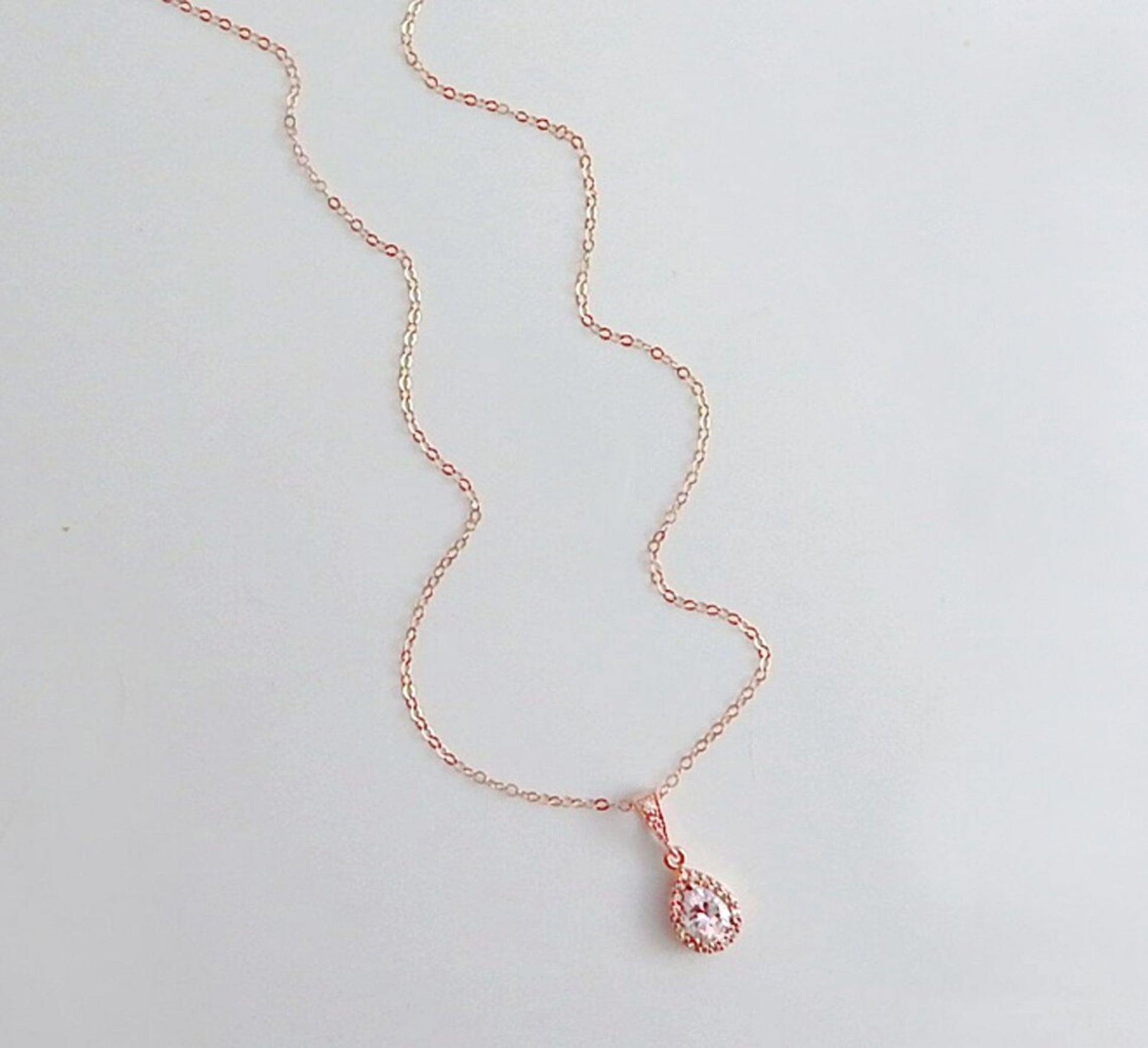 Rose gold necklace with teardrop diamond CZ pendant on a plain white background.