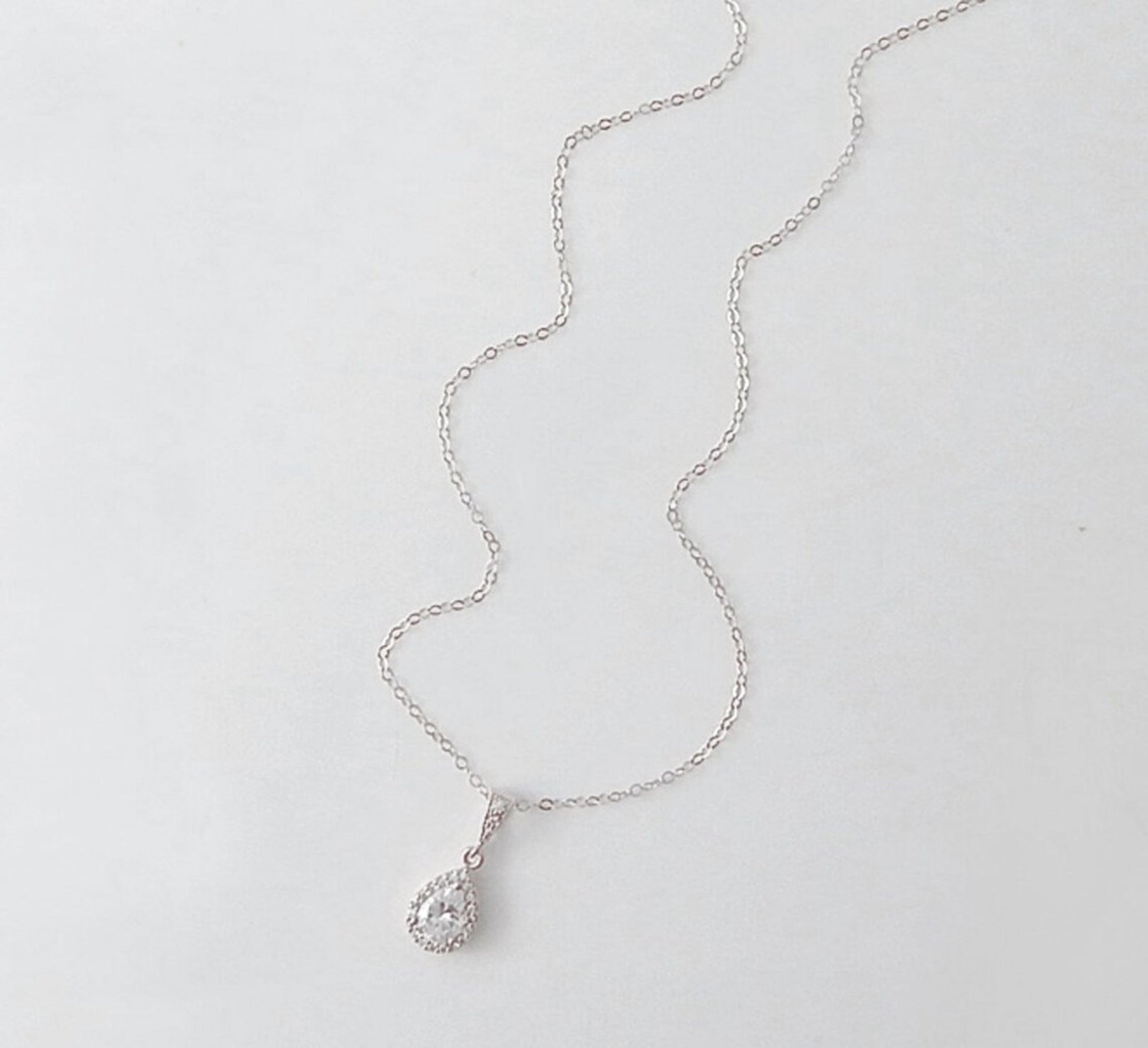 Silver necklace with a large teardrop cubic zirconia pendant on white background.
