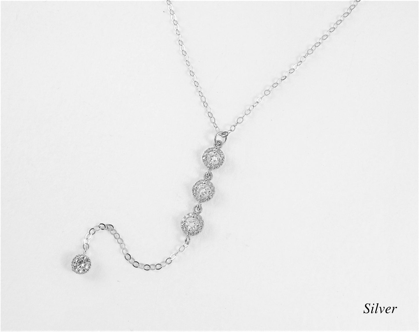Sterling silver wedding necklace with lariat design and 3 large cubic zirconia diamonds ona plain white background.