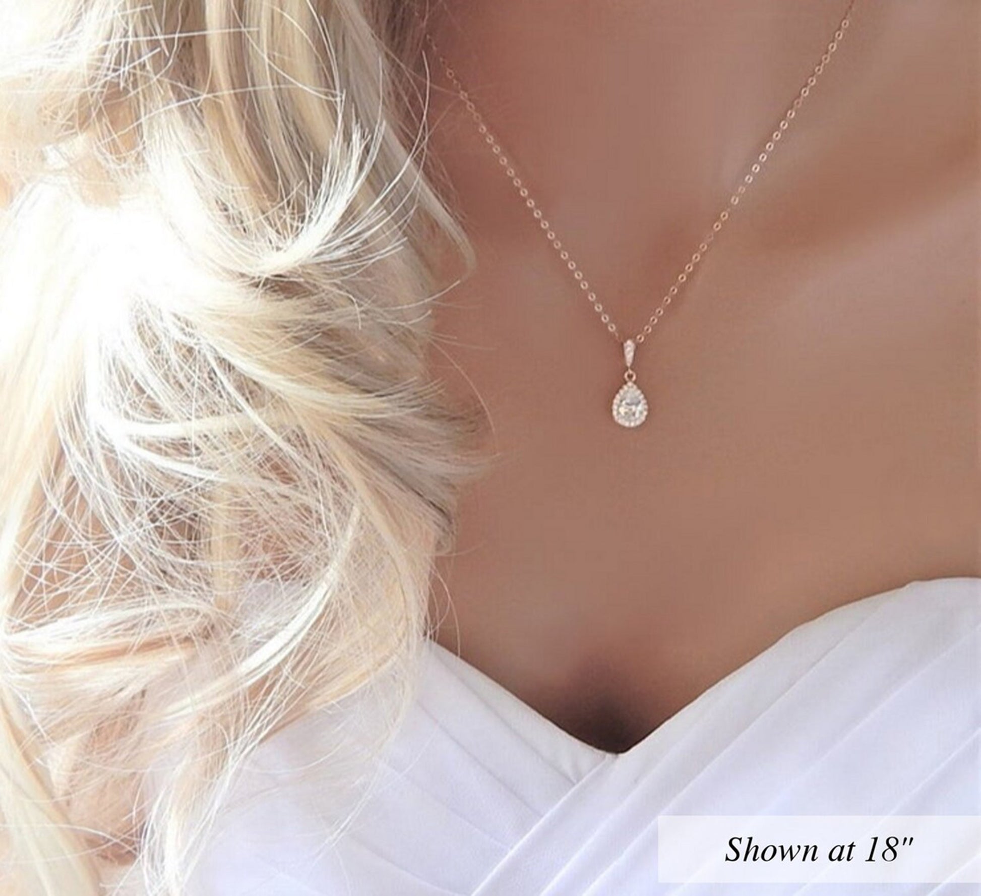 Gold wedding necklace with large pear shaped CZ diamond pendant on a bridal mannequin.