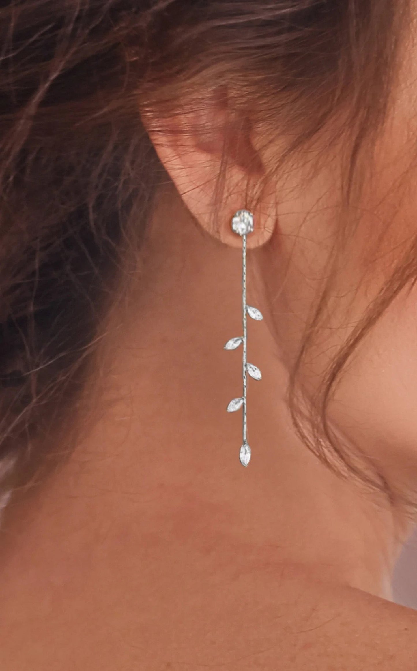 Sterling silver dangle bridal earrings with multiple diamonds are shown on a close up image of a model.
