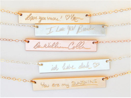 Gold filled, sterling silver, and rose gold filled jewelry engraving bar with custom handwriting messages engraved on each surface, attached to necklace chains against a plain white background.