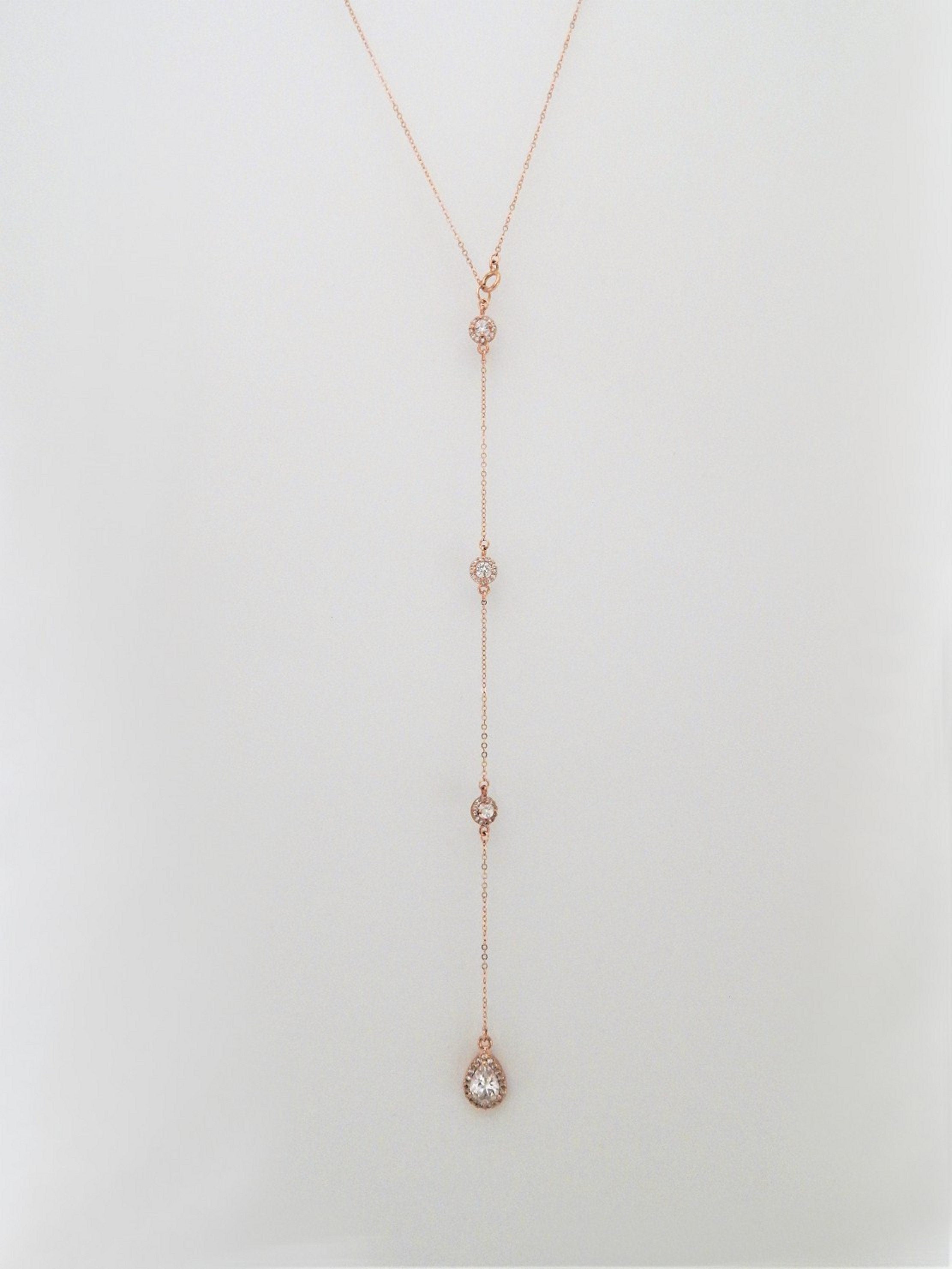 Rose gold backdrop necklace with 3 round diamond cubic zirconias and one large teardop cz on a plain white background.