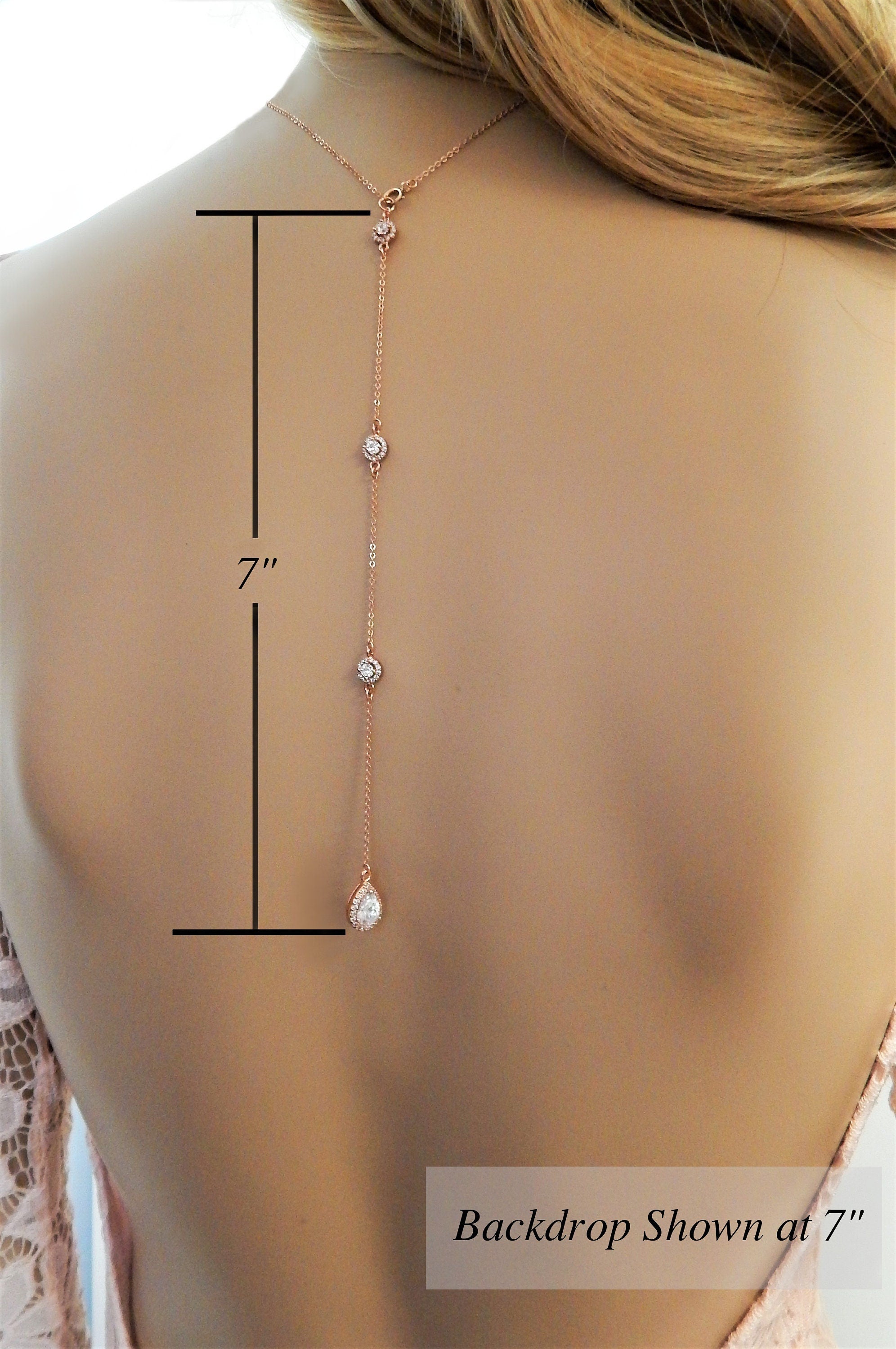 A cz diamond necklace with a 7 inch long backdrop worn on a mannequin with an open back dress.