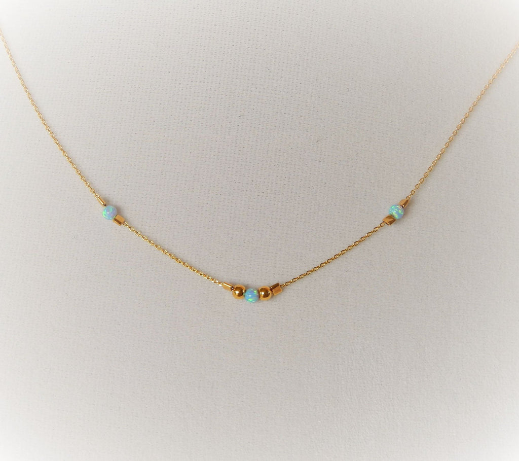 Gold choker with blue opals and gold beads on a blank textured background.