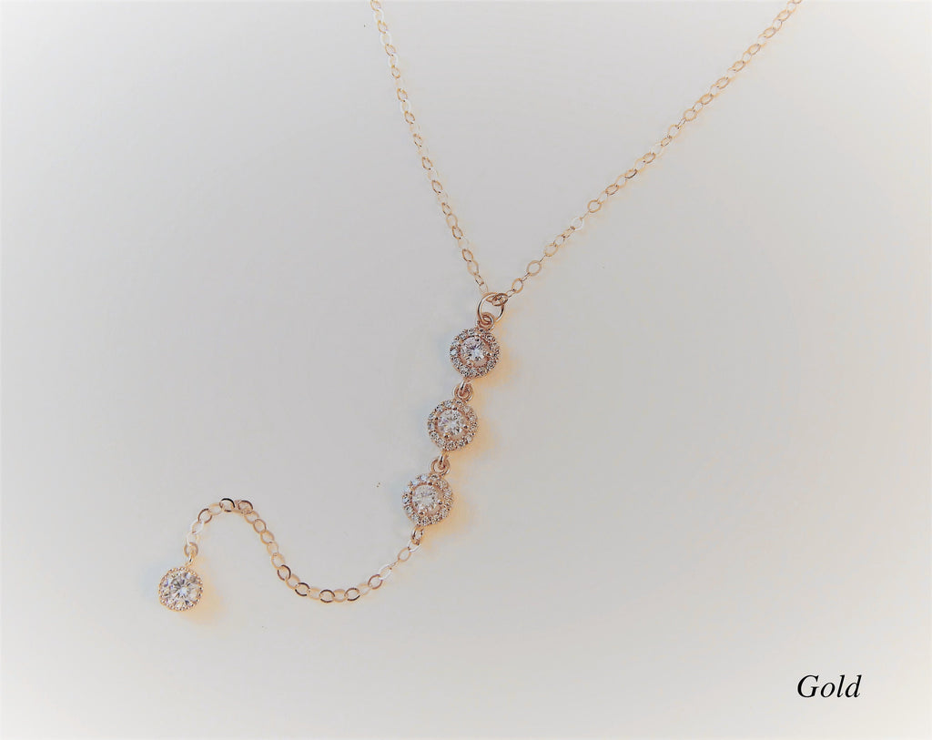 Gold filled bridesmaid necklace with 3 cubic zirconia diamonds connected in a lariat design on a plain background.