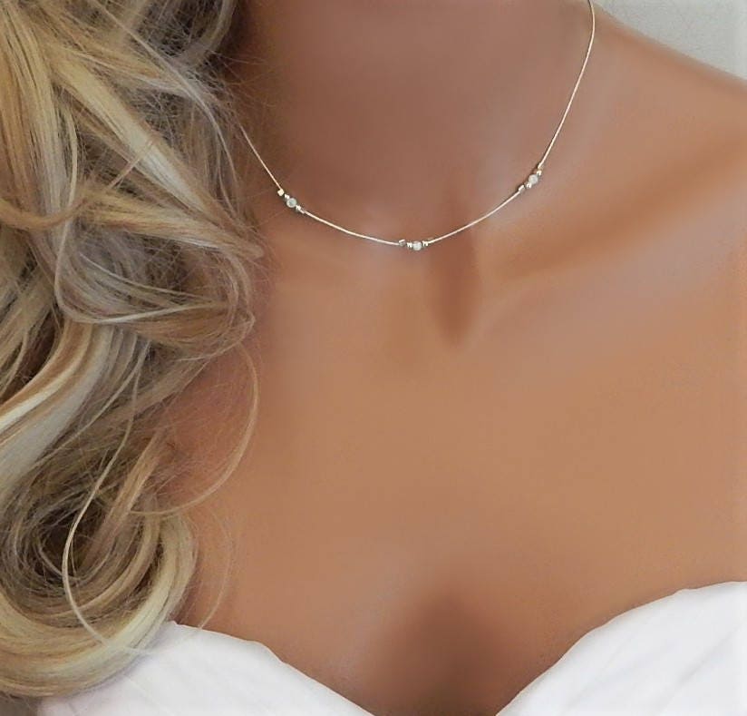 Bridal model wearing  a silver choker with opals witha wedding dress and blonde loose wavy hair.