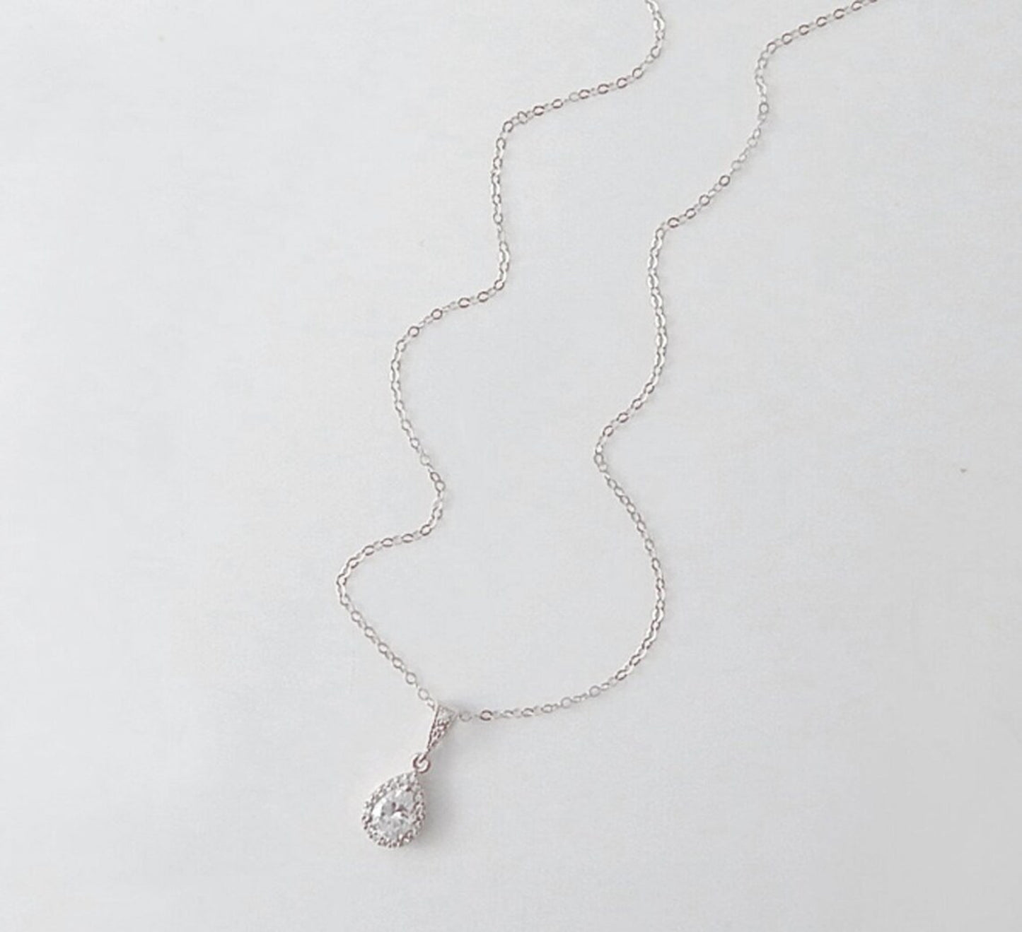 Silver necklace with a large teardrop cubic zirconia pendant on white background.