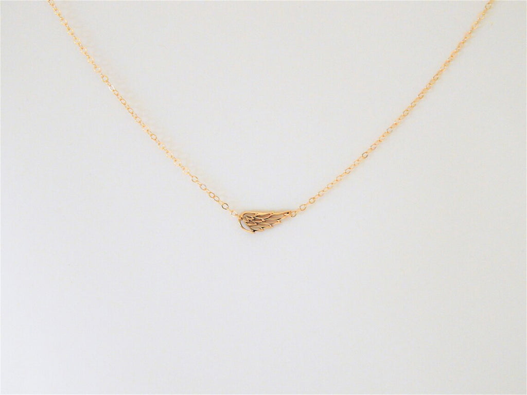 Wing charm on a simple dainty gold filled necklace chain is displayed against a plain white background to showcase the qualities of this sentimental or religious jewelry gift.