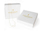 White jewelry gift boxes with a custom logo that has been foil stamped on the top of the boxes are displayed against a bright white bakground to show the packaging by custom jewelry store gilded Sapphire. 