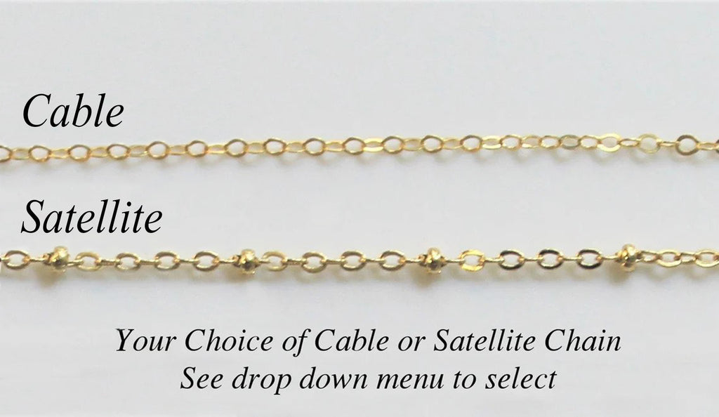 Two different gold filled necklace chain options available by custom jewerly store Gilded Sapphire with cable chain and satellite chain laying on a plain gray surface.