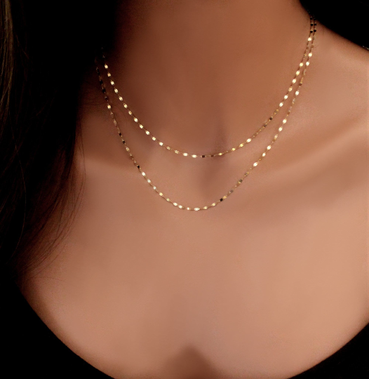 Two solid gold sequin chain necklaces on a mannequin torso.