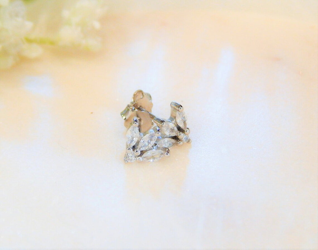 Sterling silver and hypoallergenic earring studs with marquise shaped diamonds are on a light and blurred background.